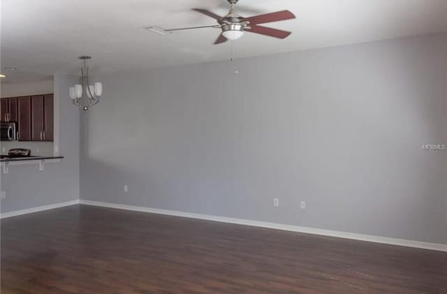 unfurnished living room featuring dark hardwood / wood-style flooring and ceiling fan with notable chandelier