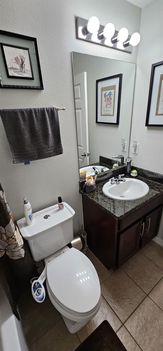 bathroom featuring tile flooring, vanity, and toilet