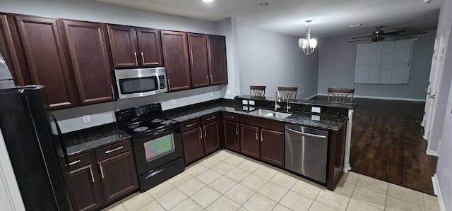 kitchen featuring kitchen peninsula, black appliances, sink, light tile floors, and pendant lighting