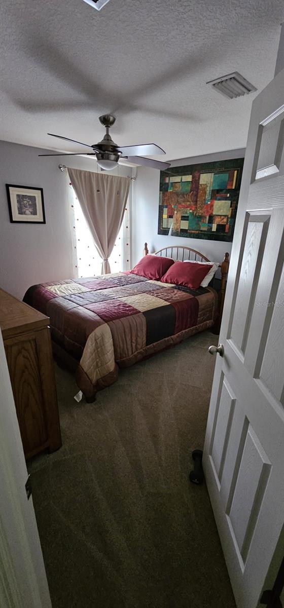 carpeted bedroom with ceiling fan and a textured ceiling