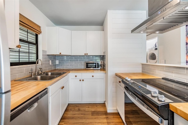 kitchen featuring wooden counters, stainless steel appliances, range hood, sink, and white cabinets