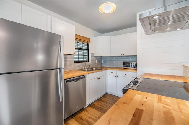 kitchen with range hood, wood counters, white cabinetry, appliances with stainless steel finishes, and light hardwood / wood-style floors