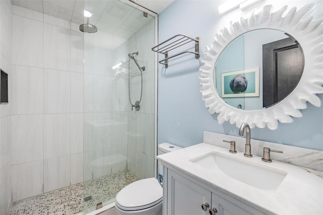 bathroom with vanity, a tile shower, and toilet