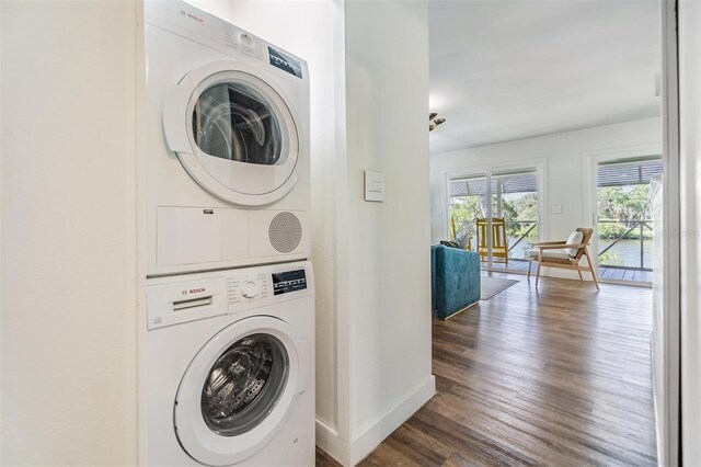 clothes washing area featuring stacked washer and dryer and dark hardwood / wood-style floors