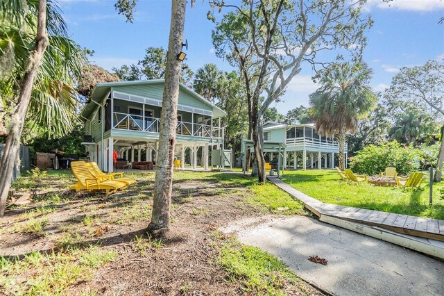 rear view of property featuring a lawn and a sunroom