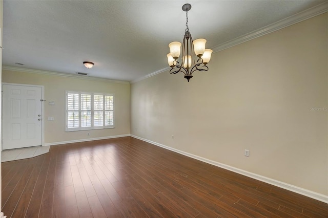 empty room with a chandelier, dark hardwood / wood-style floors, and ornamental molding