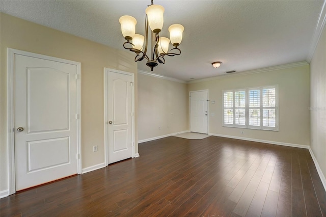 spare room featuring dark wood-type flooring, a notable chandelier, a textured ceiling, and crown molding