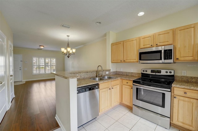 kitchen with kitchen peninsula, sink, ornamental molding, stainless steel appliances, and a notable chandelier