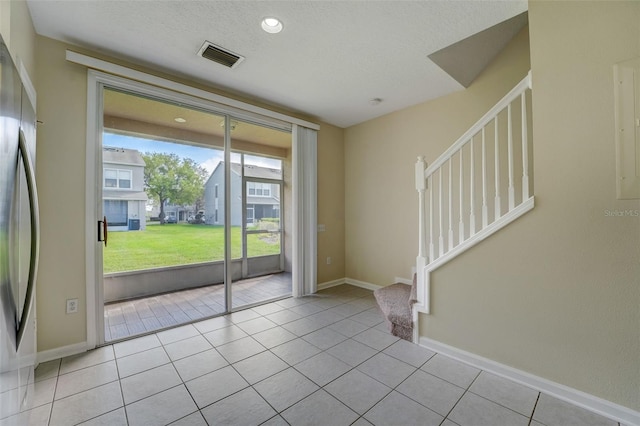 foyer entrance featuring a textured ceiling and light tile floors