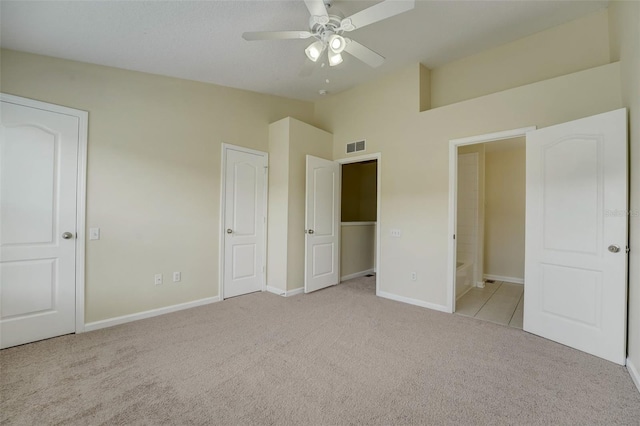 unfurnished bedroom with light colored carpet, connected bathroom, and ceiling fan