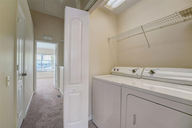 laundry room with independent washer and dryer and light colored carpet