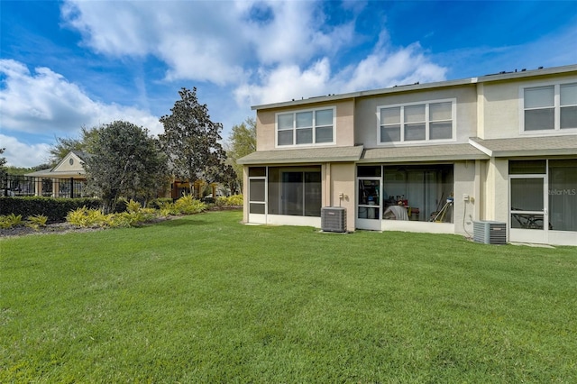 rear view of property featuring a yard, a sunroom, and central AC