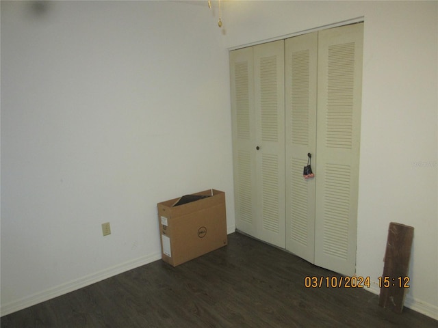 unfurnished bedroom with a closet and dark wood-type flooring