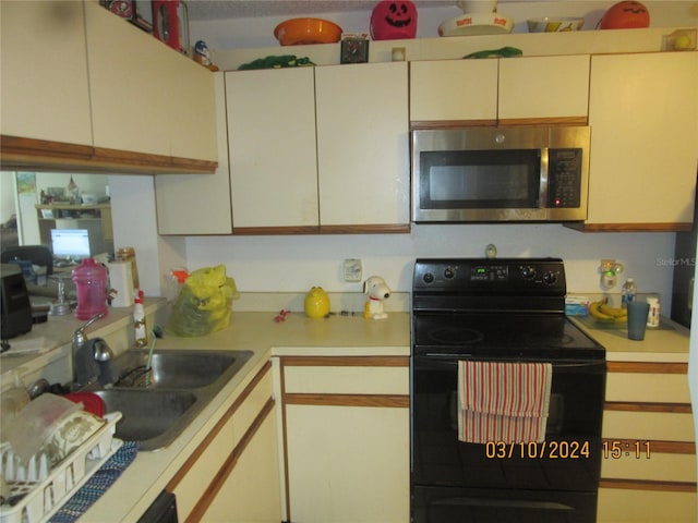 kitchen with white cabinets, black electric range, and sink