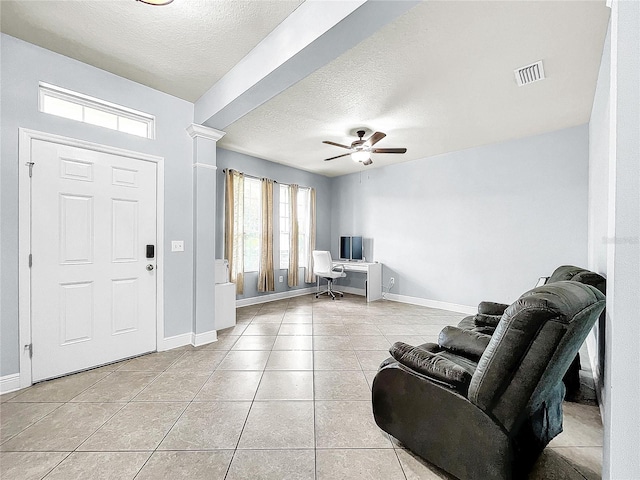 entrance foyer with light tile floors, a textured ceiling, ornate columns, and ceiling fan