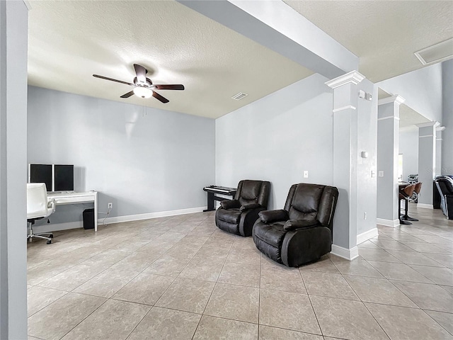 living area with a textured ceiling, decorative columns, light tile flooring, and ceiling fan