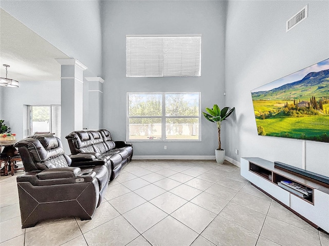 living room with a wealth of natural light, light tile floors, and a towering ceiling