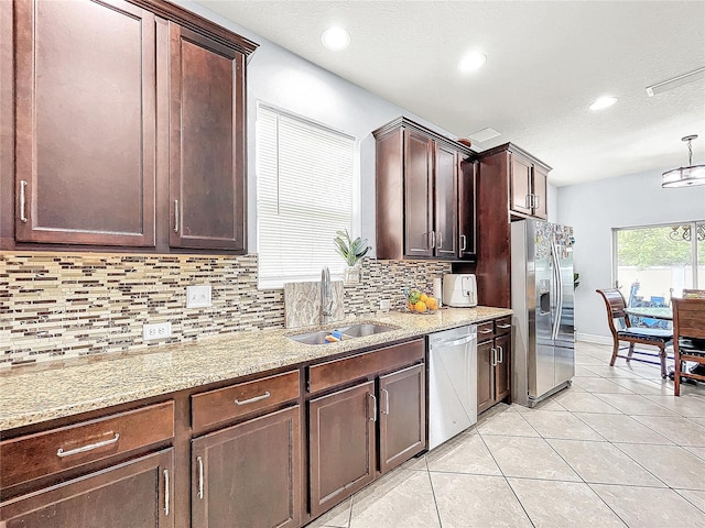 kitchen with light tile floors, light stone countertops, appliances with stainless steel finishes, backsplash, and sink