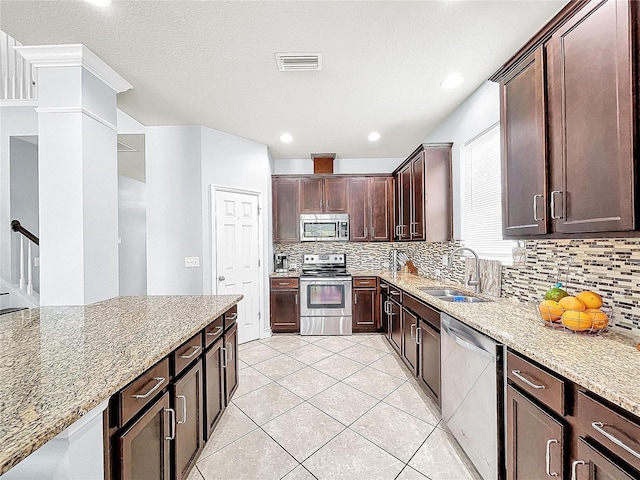 kitchen with appliances with stainless steel finishes, backsplash, light stone countertops, and sink