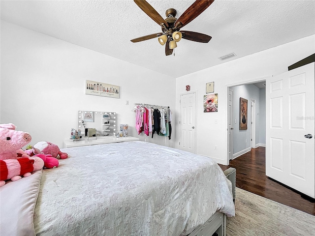 bedroom with ceiling fan, a textured ceiling, and dark hardwood / wood-style flooring