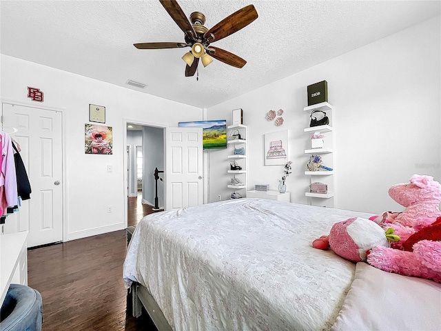 bedroom with dark hardwood / wood-style floors, a textured ceiling, and ceiling fan