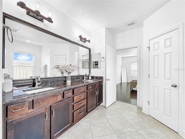 bathroom with dual bowl vanity, tile flooring, and a textured ceiling