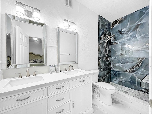 bathroom with double sink vanity, tile floors, toilet, and tiled shower