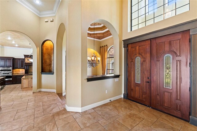 tiled entrance foyer with an inviting chandelier, crown molding, and a towering ceiling