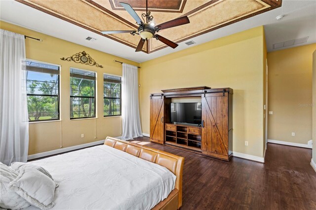 bedroom with a barn door, dark wood-type flooring, and ceiling fan