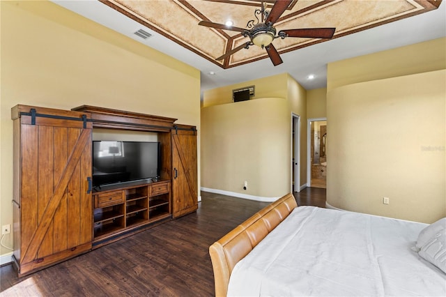 bedroom featuring a barn door, ceiling fan, and dark hardwood / wood-style floors