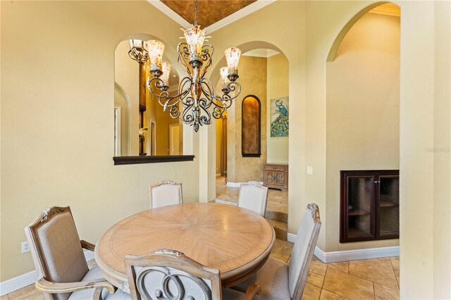 dining space with ornamental molding, a notable chandelier, and light tile floors