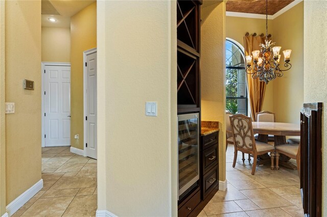 hall featuring wine cooler, a chandelier, crown molding, and light tile flooring