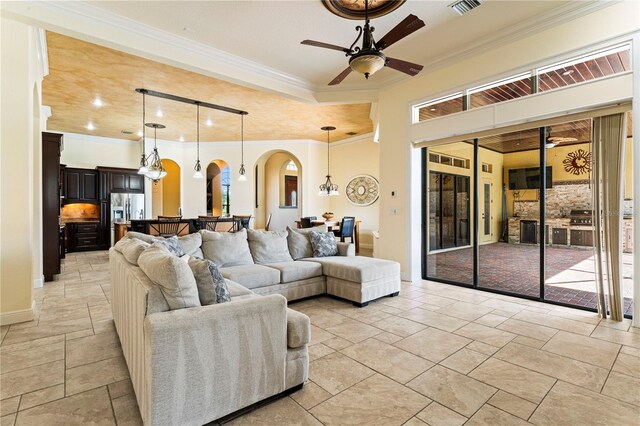 tiled living room with ornamental molding, ceiling fan with notable chandelier, and a wealth of natural light