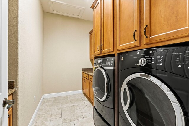 laundry room featuring washer and clothes dryer, cabinets, and light tile floors