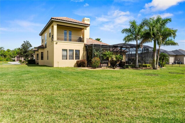 rear view of property featuring a balcony, a lanai, and a lawn