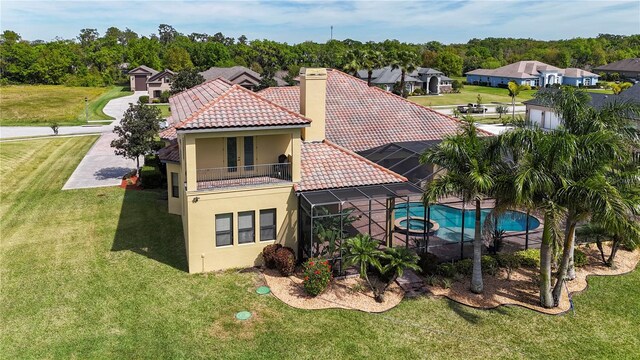 back of property featuring a balcony and a lawn