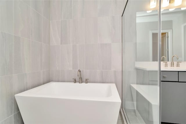 bathroom featuring vanity, a tub to relax in, and tile walls