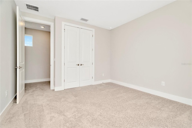 unfurnished bedroom with light colored carpet and a closet