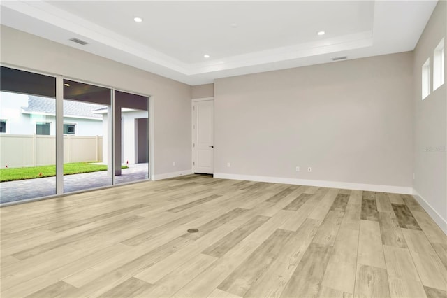 unfurnished room with a raised ceiling and light wood-type flooring