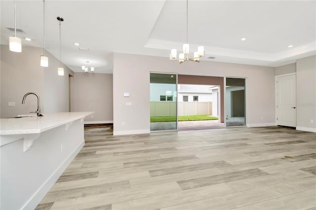 kitchen featuring sink, decorative light fixtures, and light hardwood / wood-style flooring