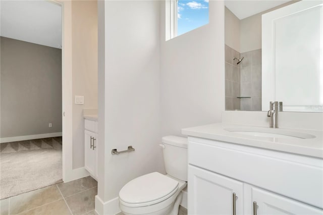 bathroom with tiled shower, tile patterned flooring, vanity, and toilet