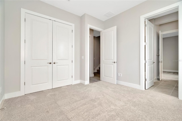 unfurnished bedroom with a closet and light colored carpet