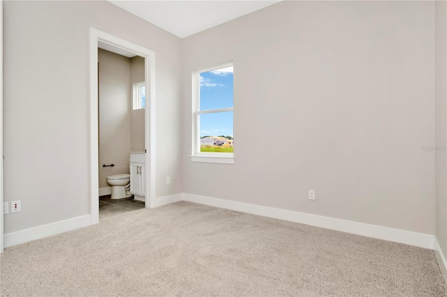 unfurnished bedroom with light colored carpet and connected bathroom