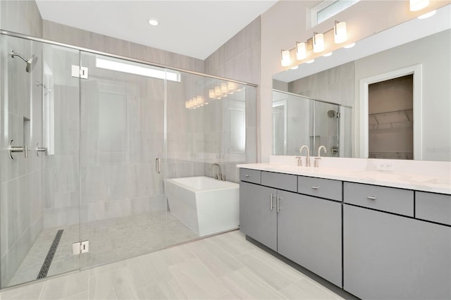 bathroom with tile patterned floors, vanity, shower with separate bathtub, and tile walls