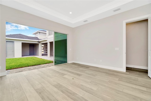 unfurnished room with a raised ceiling and light hardwood / wood-style flooring