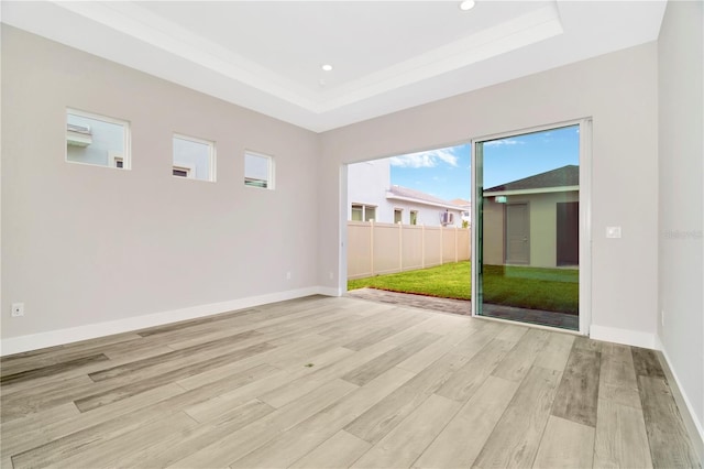 spare room with light wood-type flooring and a raised ceiling