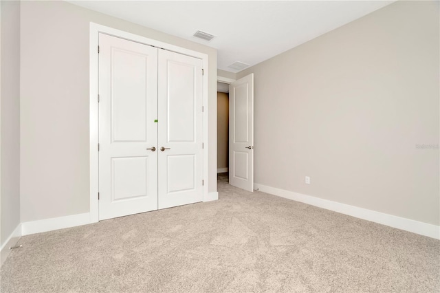 unfurnished bedroom featuring light colored carpet and a closet