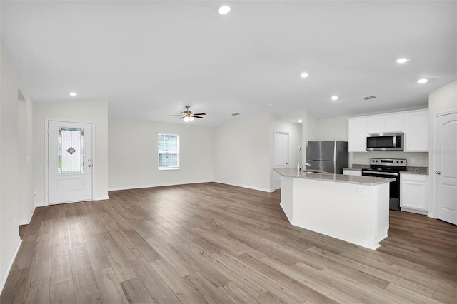 kitchen with ceiling fan, appliances with stainless steel finishes, light wood-type flooring, white cabinets, and a center island with sink