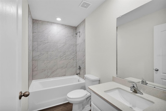 full bathroom with hardwood / wood-style flooring, toilet, tiled shower / bath combo, and vanity