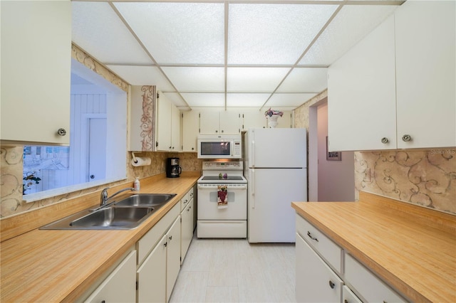 kitchen with white appliances, sink, light tile floors, a paneled ceiling, and backsplash